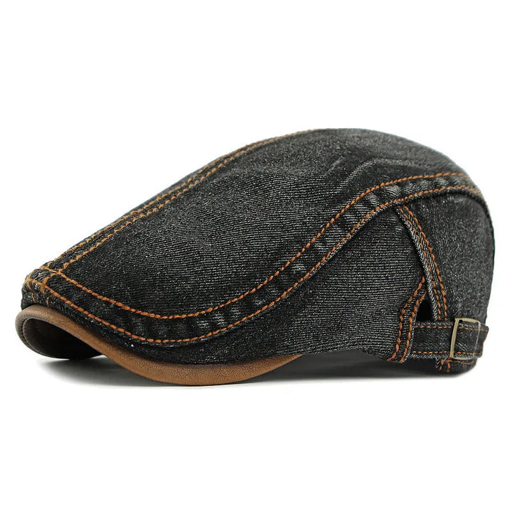 A dark gray unisex denim flat cap with visible orange stitching, a brown underside on the brim, and an adjustable strap at the back offers both style and sun protection.