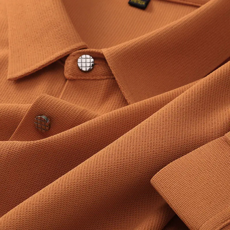 Close-up of a textured, rust-orange wrinkle-resistant shirt with metallic grid-patterned buttons, showing detailed fabric weave and folded areas for a clear view of the material and button design.