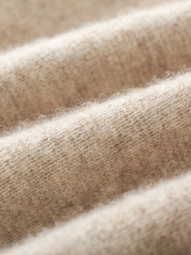 Close-up view of soft, beige, knitted fabric from a men's casual cardigan, with visible fibers and textured surface, arranged in gentle, undulating folds.