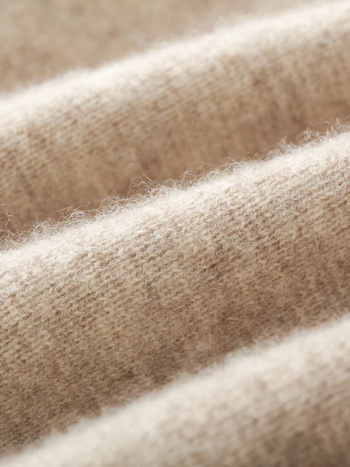Close-up view of soft, beige, knitted fabric from a men's casual cardigan, with visible fibers and textured surface, arranged in gentle, undulating folds.