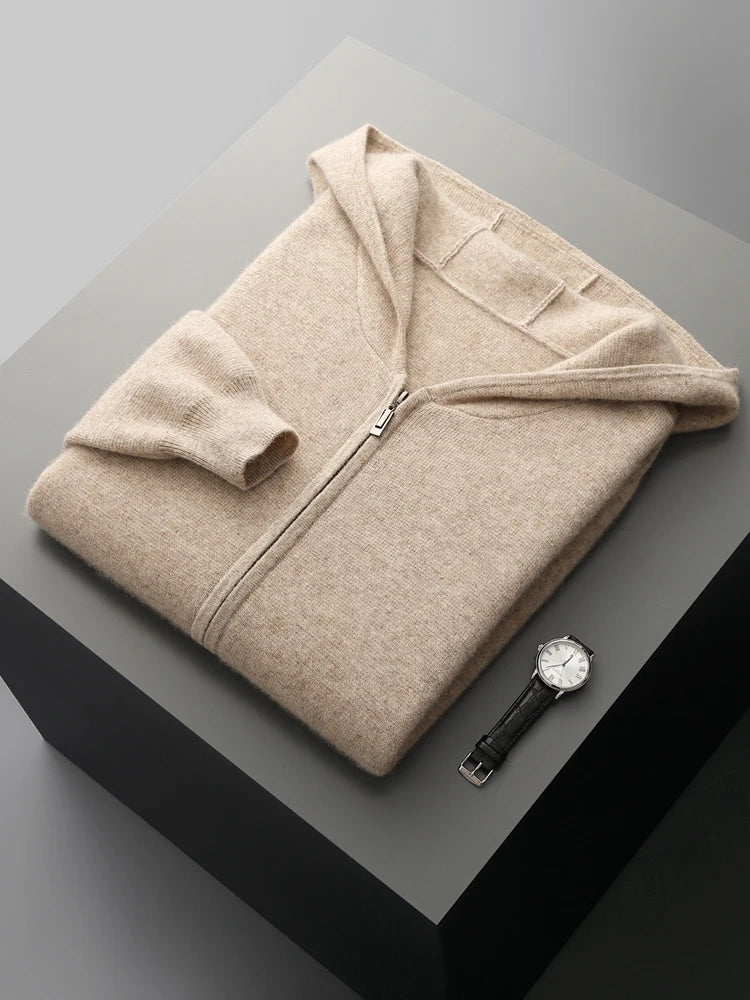 A beige zip-up hoodie neatly folded on a gray surface, with a black leather strap wristwatch placed beside it—perfect for pairing with your favorite autumn winter cardigan.