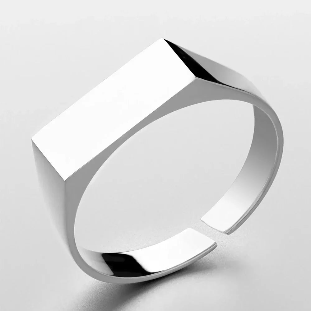 A minimalist, modern silver ring in scratch-resistant stainless steel with a wide, flat rectangular top and a polished, reflective surface, shown on a plain white background.