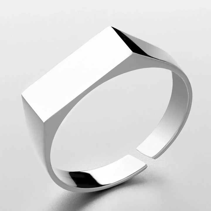 A minimalist, modern silver ring in scratch-resistant stainless steel with a wide, flat rectangular top and a polished, reflective surface, shown on a plain white background.