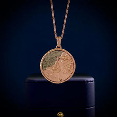 A gold zodiac necklace with an engraved circular medallion featuring clouds and a set of scales, displayed against a dark blue background atop a dark jewelry box—an elegant piece of astrology jewelry.