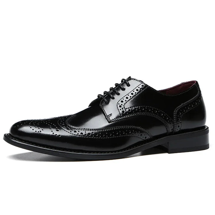 A shiny black premium leather brogue wingtip dress shoe with detailed broguing, lace-up closure, cushioned insole, and a low heel, photographed on a white background.