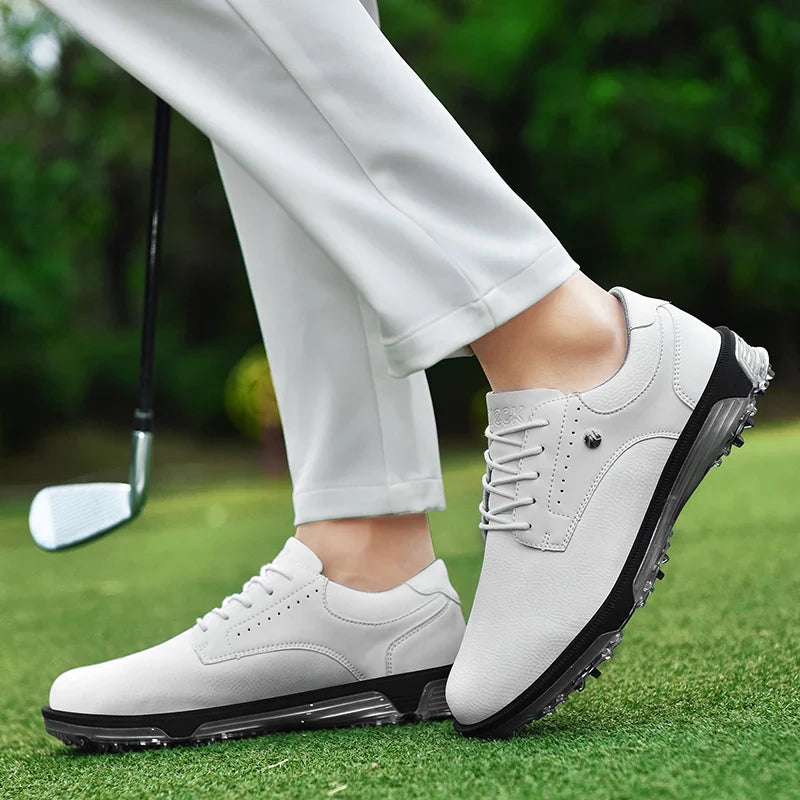 Person wearing white golf shoes with a breathable mesh lining and white pants stands on green grass, holding a golf club. The blurred greenery backdrop highlights the shoes design, texture, and comfort.