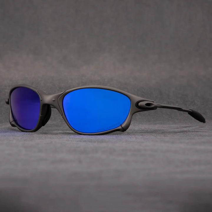 A pair of black-framed polarized sunglasses with vibrant blue mirrored lenses, designed for UV protection, is displayed on a gray surface with a neutral gray background.