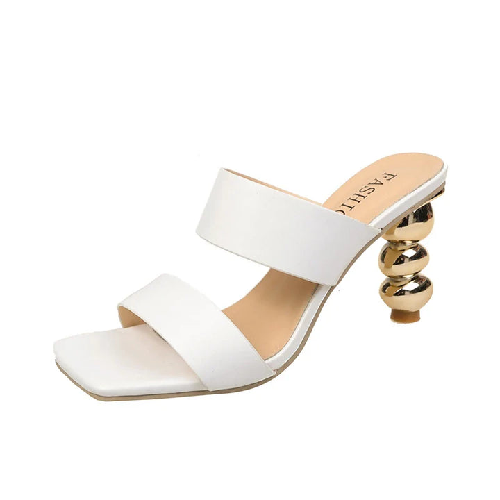 A stylish white heeled sandal crafted from premium leather, featuring two wide straps, a square toe, and a unique gold spiral-shaped heel.