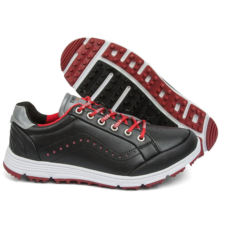 A pair of black athletic golf footwear with red and white accents, red laces, gray heel detailing, and textured red and black rubber soles. One shoe is upright; the other displays the sole featuring advanced cleat technology.