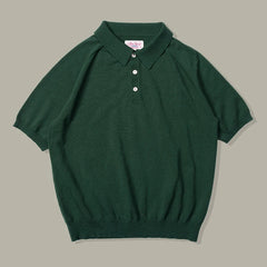 A short-sleeve, dark green classic style polo shirt with a collar, three white buttons, and ribbed cuffs and hem, laid flat on a neutral background.