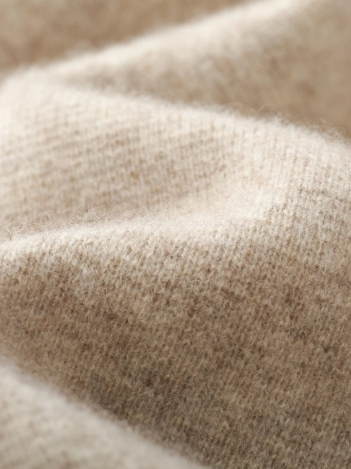 Close-up of a soft, beige wool cardigan fabric, showing its textured, fuzzy surface with gentle folds and subtle shadows—perfect for a cozy autumn winter sweater.