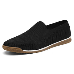 Black slip-on men's casual shoes with a breathable knitted texture, brown rubber sole, white midsole accent, and a low-profile design, shown on a white background.
