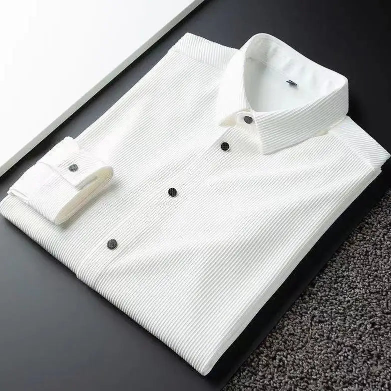 A neatly folded white dress shirt with subtle vertical stripes and black buttons, crafted from ultra soft fabric, placed on a black surface next to a white panel and a textured gray carpet.