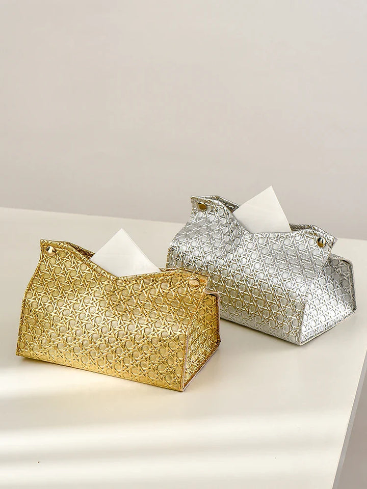 Gold and silver Glymmer Tissue Box holders with geometric patterns, each holding white tissues, are placed on a white surface against a neutral background.