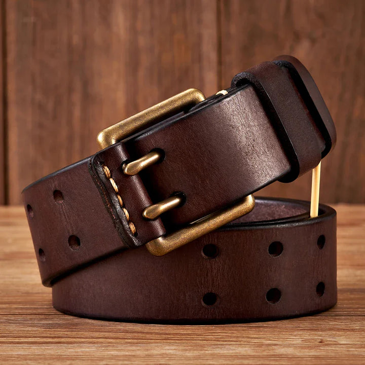 A durable cowhide leather belt in dark brown, featuring a brass buckle and multiple holes, is coiled on a wooden surface with a wooden backdrop.