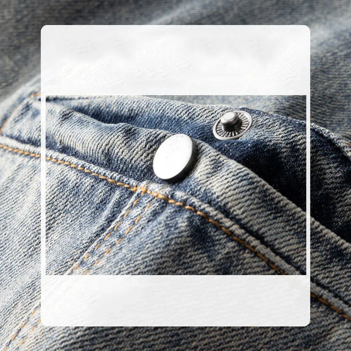 Close-up of classic fit blue denim jeans pocket with visible stitching and two metal rivets, one silver and one black, highlighting the stone washed texture and detail of the fabric.