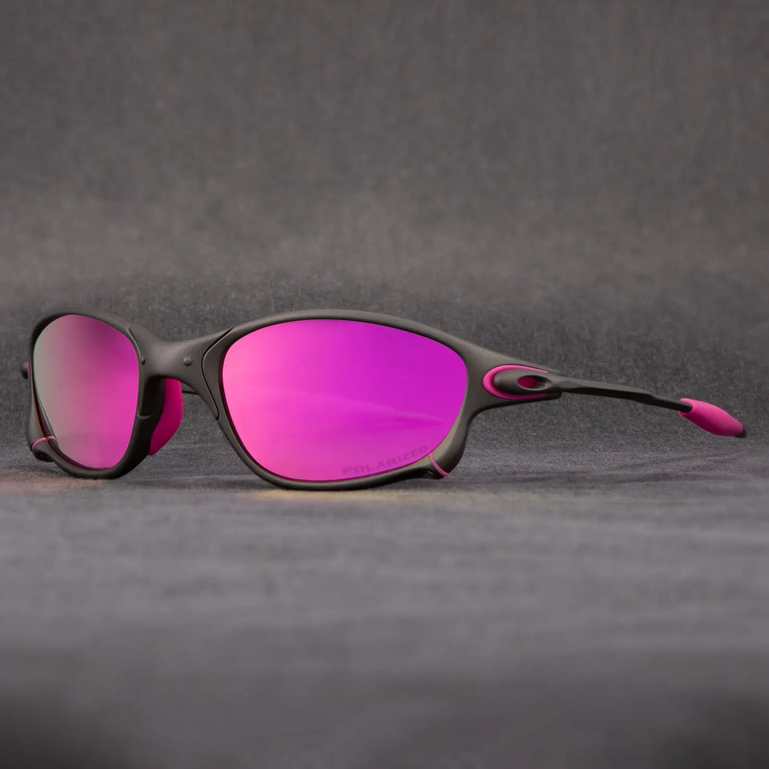 A pair of sporty outdoor eyewear with black frames and pink accents, featuring reflective pink lenses and UV protection, displayed on a gray surface with a soft gray background.