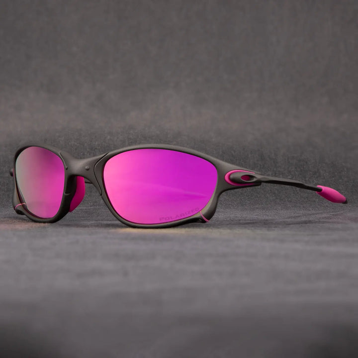 A pair of sporty outdoor eyewear with black frames and pink accents, featuring reflective pink lenses and UV protection, displayed on a gray surface with a soft gray background.