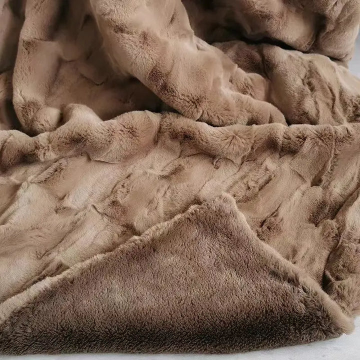 A close-up view of a soft, brown, plush faux fur blanket with a textured, cozy surface and folded edges, showcasing the warmth and comfort of this eco-friendly blanket.