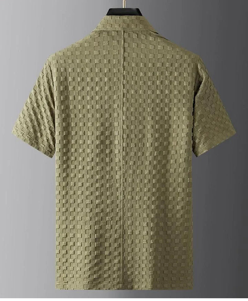 A short-sleeve olive green shirt with a textured, checkered pattern is displayed on a hanger against a plain gray background. Crafted from ultra-soft fabric, the shirt is shown from the back.