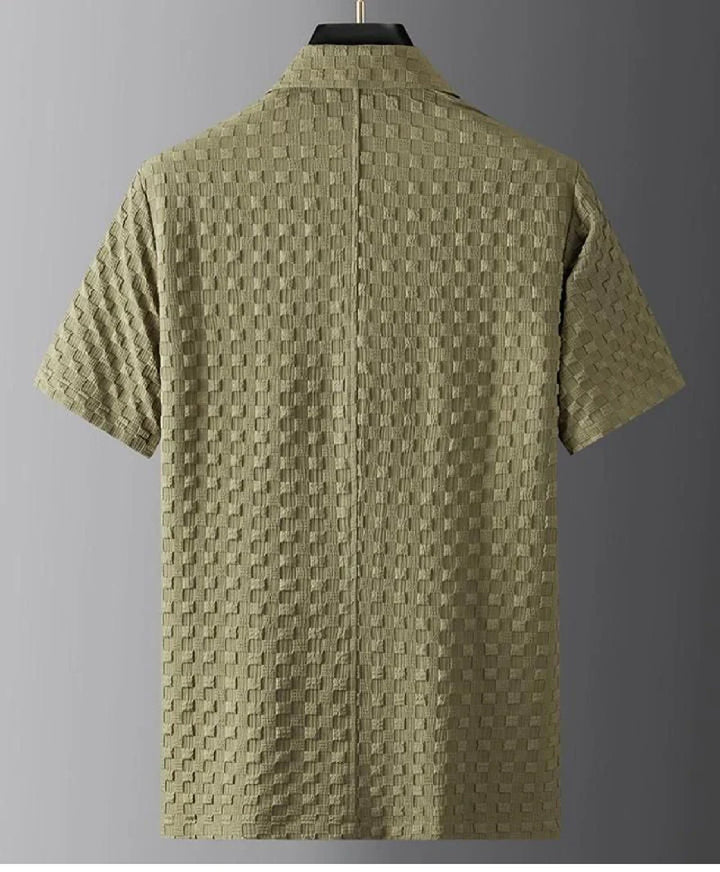 A short-sleeve olive green shirt with a textured, checkered pattern is displayed on a hanger against a plain gray background. Crafted from ultra-soft fabric, the shirt is shown from the back.
