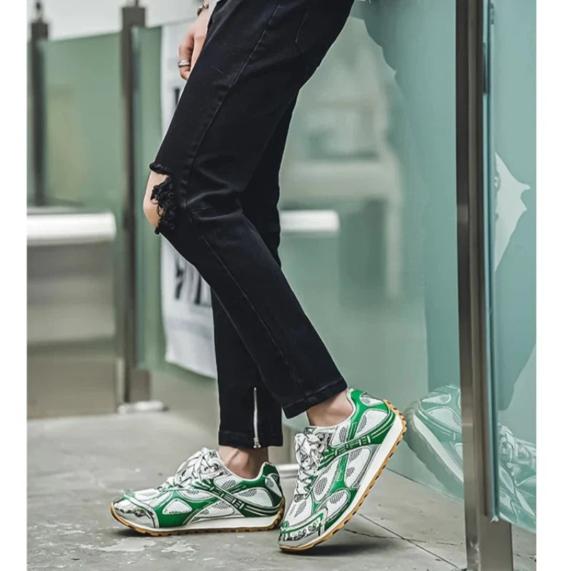 A person wearing black ripped skinny jeans and green-and-white sneakers with a non-slip outsole stands by a glass barrier. Only their legs and feet are visible, with the shoes and jeans prominently featured.