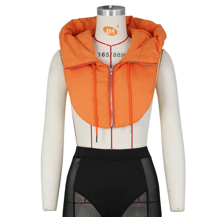 A dress form displays an orange hooded vest with a front zipper and wide collar, crafted from durable material, paired with high-waisted black mesh shorts. The background is plain white.