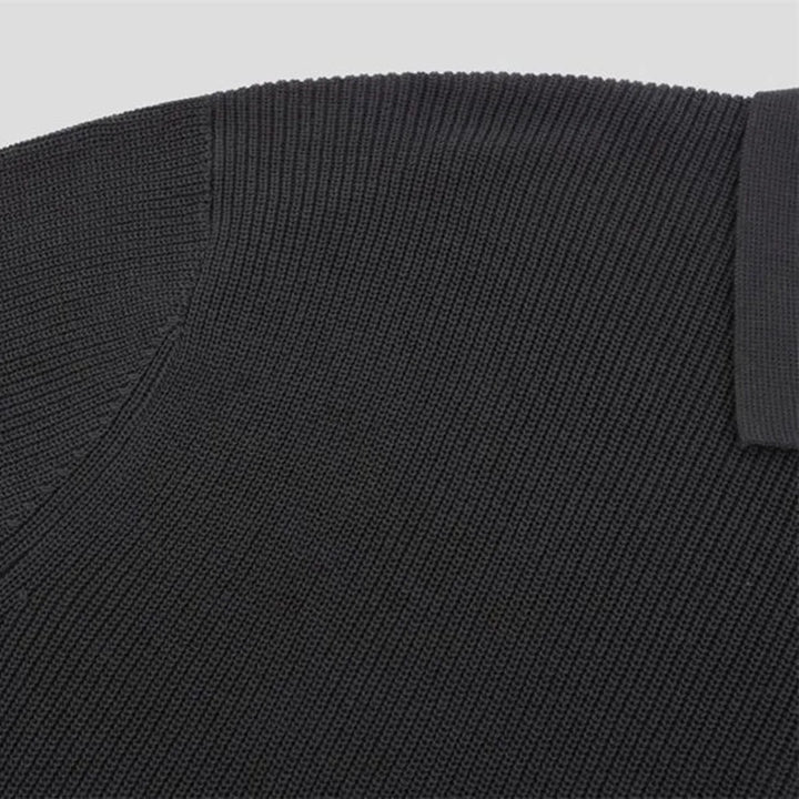 Close-up of a black ribbed knit fabric, possibly part of a viscose polo, showing fine texture and ribbed detailing along the collar and shoulder seam.