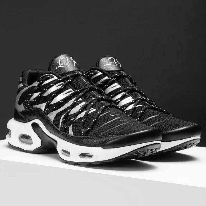 A pair of black athletic sneakers with white accents and a wavy striped pattern, featuring a breathable mesh upper, thick white soles with visible air cushions, displayed on a white surface against a dark background.