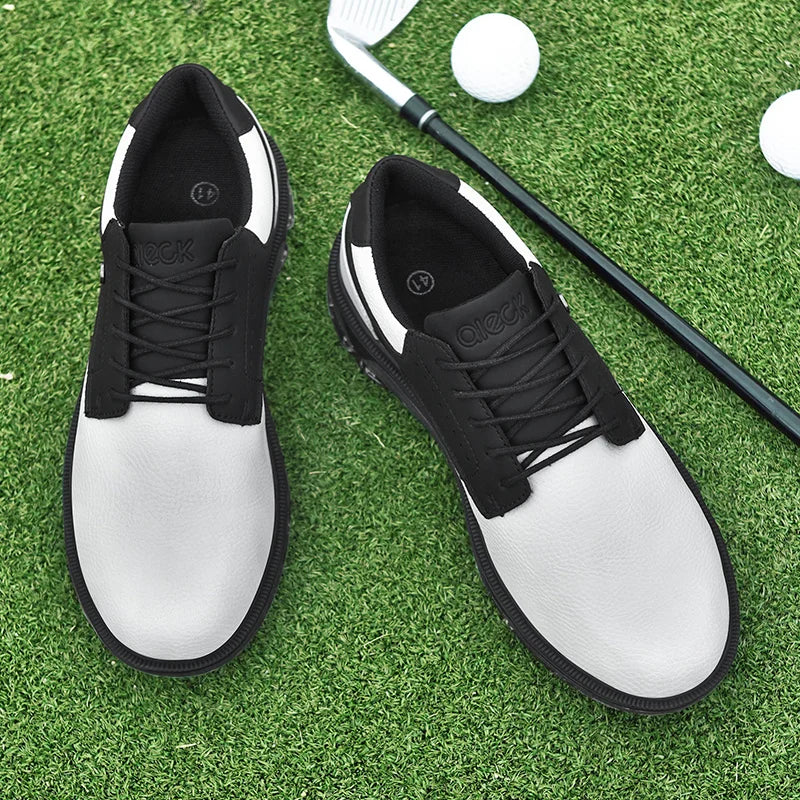 A pair of white and black golf shoes with a reinforced toe cap rest on artificial grass, alongside a golf club and two golf balls.