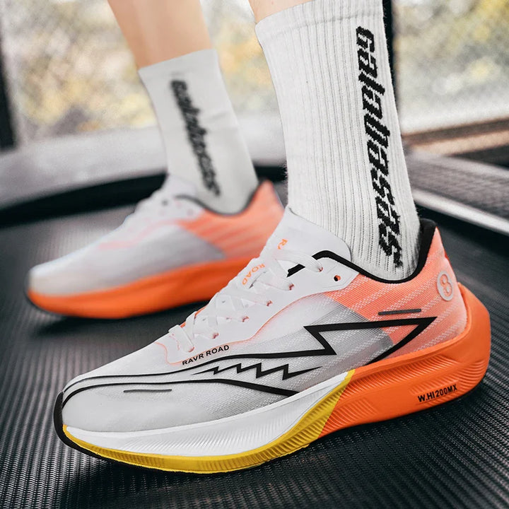 A person wearing white and orange running shoes with black zigzag details stands on a treadmill, featuring a shock-absorbing sole. They wear white socks with bold black text, emphasizing comfort during exercise or running activity.