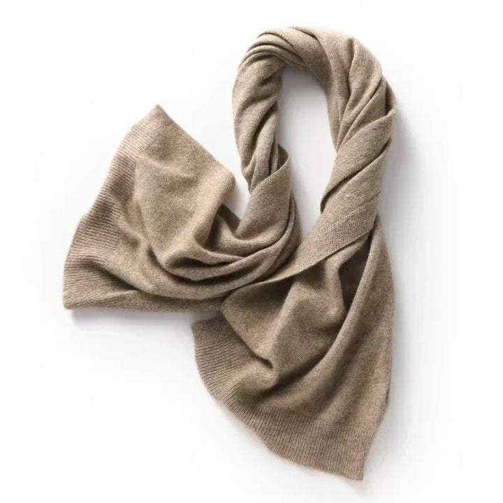 A soft, light brown wool scarf is laid out on a white surface, its ends loosely draped and slightly curled, perfect for autumn winter layering and showing off its cozy texture.