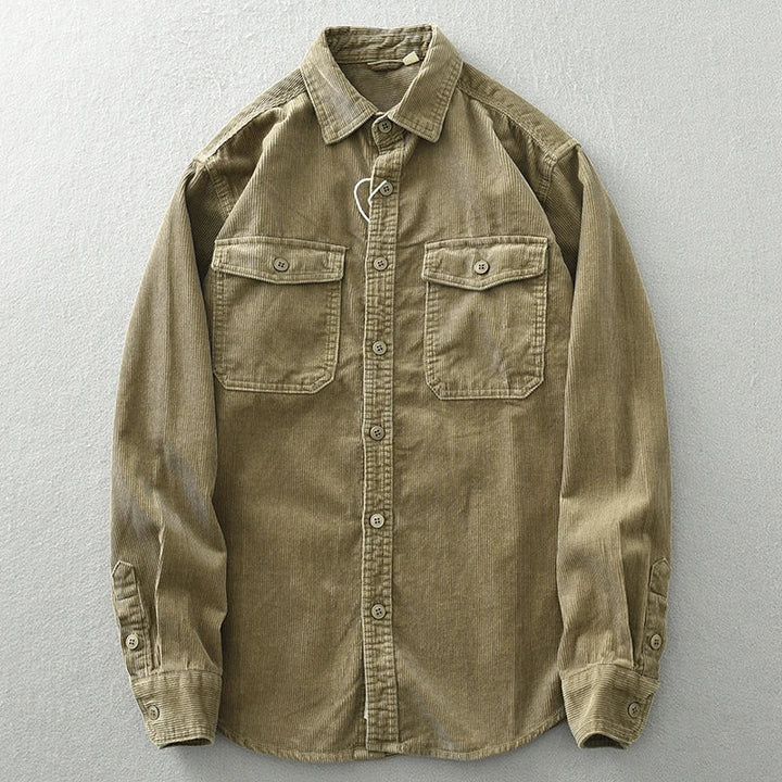 A khaki-colored, long-sleeve button-up shirt with two chest pockets and subtle corduroy detailing, displayed flat on a light gray surface.