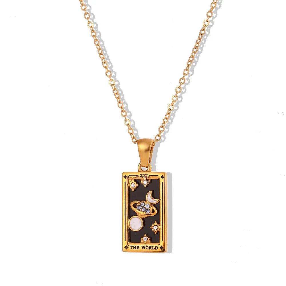 The Solaris Pendant Necklace features a striking rectangular pendant in 18K gold-plated finish, adorned with celestial symbols on a black background and inscribed “THE WORLD” at the bottom. Blue enamel accents complete this enchanting piece.