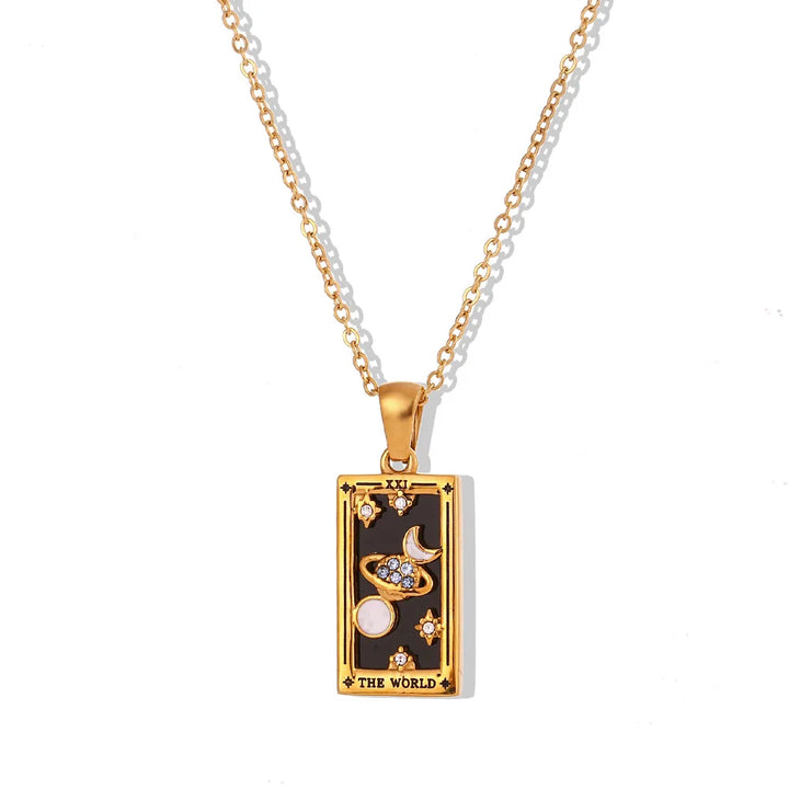 The Solaris Pendant Necklace features a striking rectangular pendant in 18K gold-plated finish, adorned with celestial symbols on a black background and inscribed “THE WORLD” at the bottom. Blue enamel accents complete this enchanting piece.