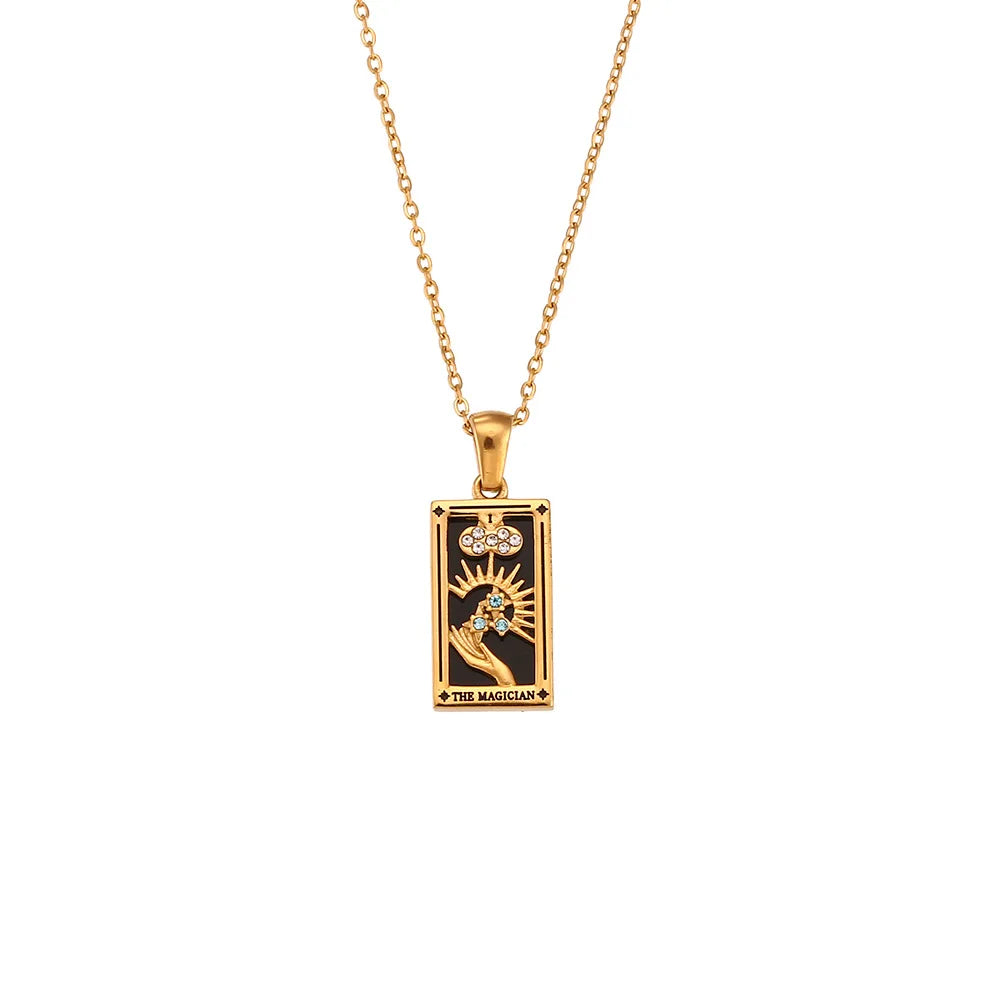 The Solaris Pendant Necklace is an 18K gold-plated necklace with a rectangular pendant featuring a tarot card design. The pendant shows a hand holding a wand, a sunburst, and THE MAGICIAN on a striking black background.