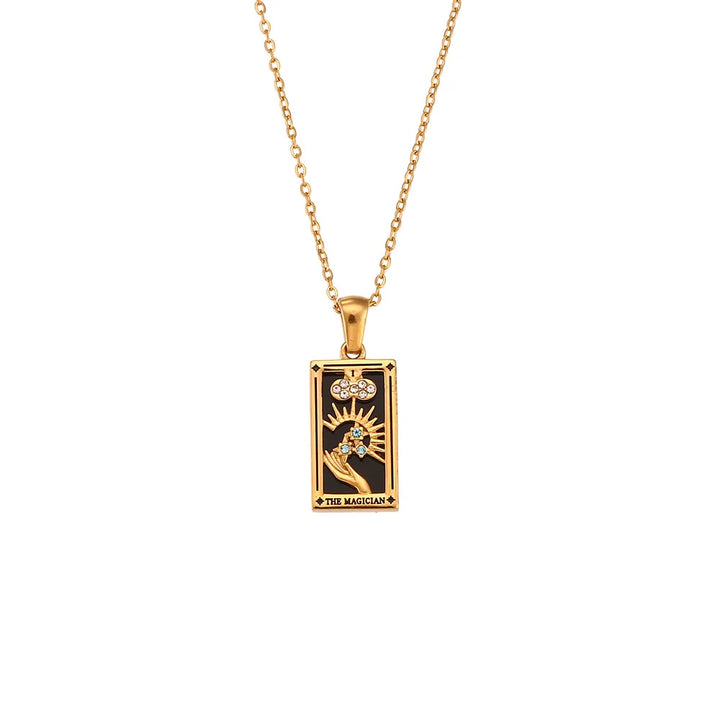 The Solaris Pendant Necklace is an 18K gold-plated necklace with a rectangular pendant featuring a tarot card design. The pendant shows a hand holding a wand, a sunburst, and THE MAGICIAN on a striking black background.