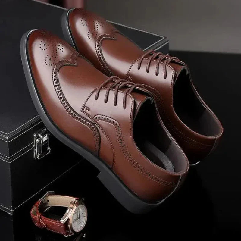 A pair of premium leather shoes with brogue detailing, featuring decorative stitching and perforations, displayed on a black surface next to a black box and a brown wristwatch with a white face.