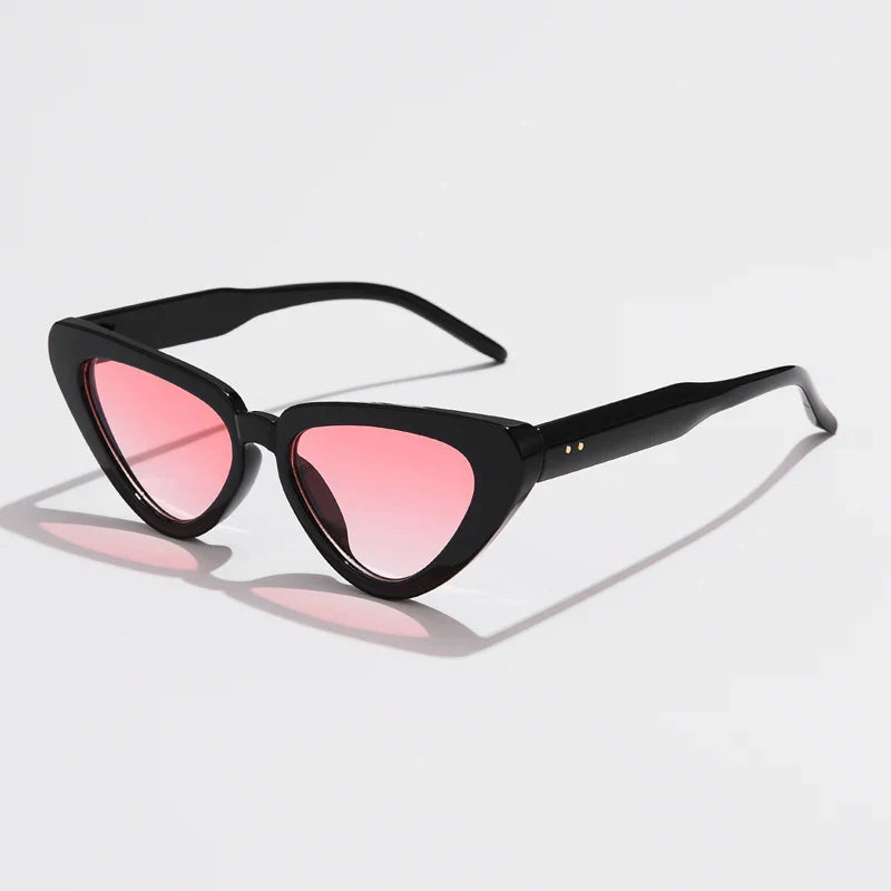 A pair of black, cat-eye sunglasses with pink-tinted lenses and UV400 sun protection is displayed on a white surface.