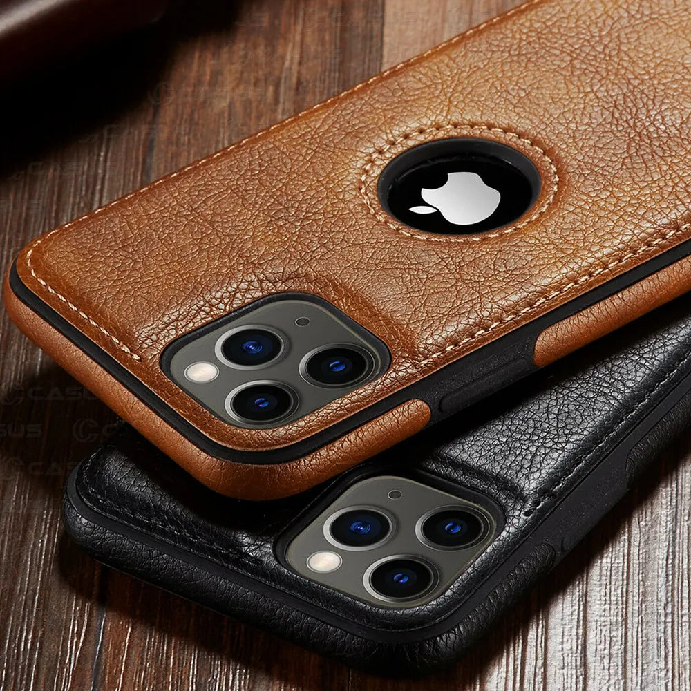 Two smartphones in brown and black luxury leather phone cases rest on a wooden surface. Both slim protective cases feature a circular cutout revealing the Apple logo, openings for the triple camera, and are wireless charging compatible.