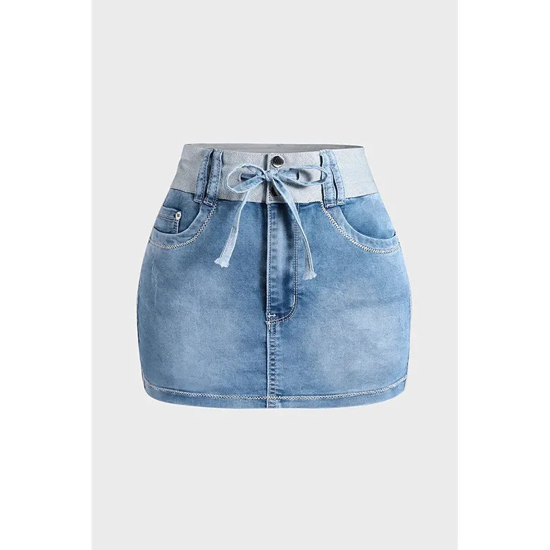 Light blue high waist denim skirt crafted from premium cotton, featuring a front tie belt, visible stitching, front pockets, and a button closure. Displayed against a plain gray background.