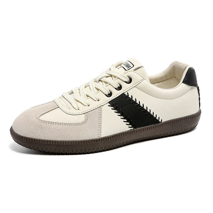A white and beige sneaker with a black zigzag stripe on the side, white laces, a beige suede toe cap, EVA midsole cushioning, and a brown textured rubber sole for comfort and effortless style.