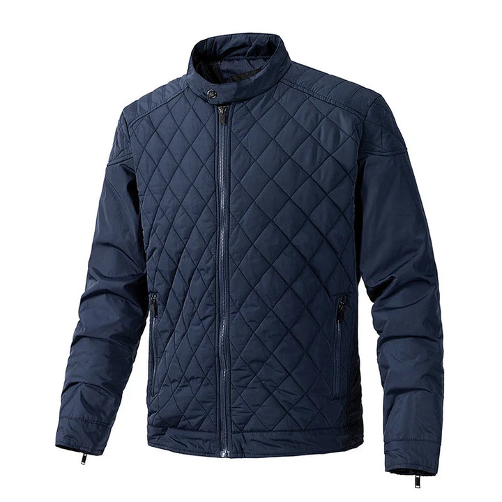 A navy blue slim-fit jacket with a front zipper, two zippered side pockets, and a short standing collar. The jacket features cotton insulation, a diamond-stitched pattern on the front, and a smooth finish on the sleeves.
