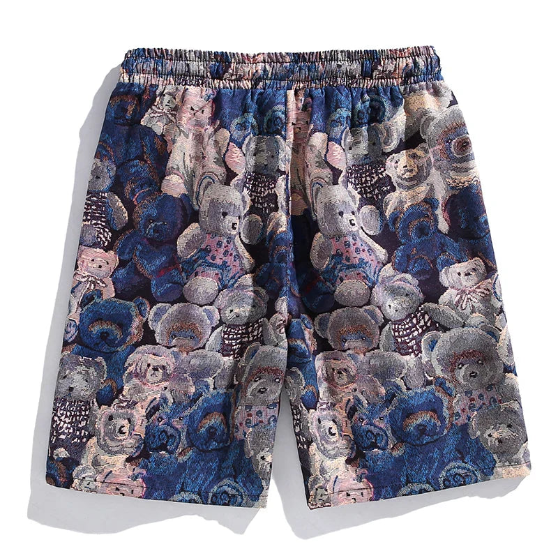 A pair of premium quality shorts with an elastic waistband, featuring a colorful, textured pattern of teddy bears in shades of blue, pink, and beige.