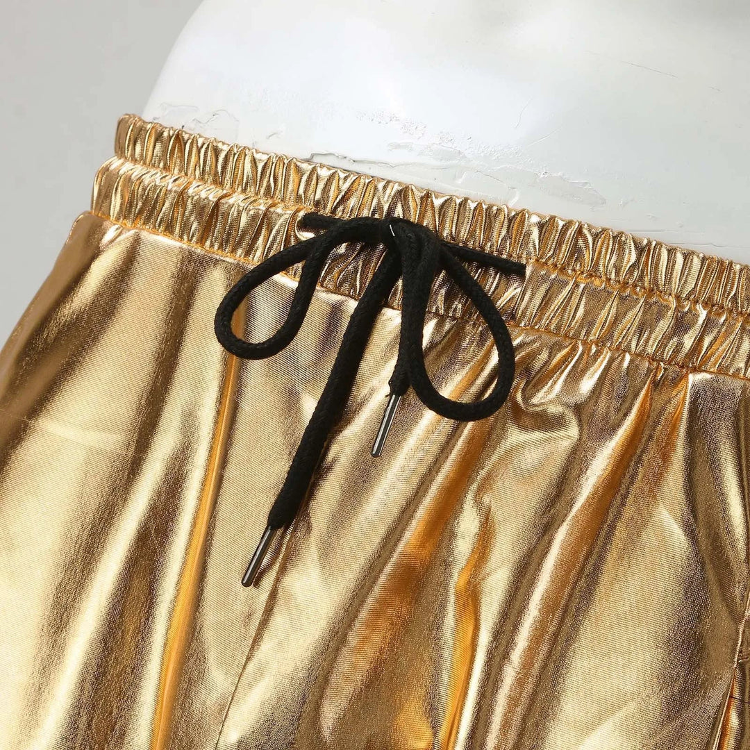 Close-up of gold metallic pants crafted from lightweight metallic fabric with an elastic waistband and black drawstring tied in a bow, featuring a stylish tapered leg, displayed on a white mannequin.