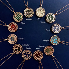 Twelve gold astrology jewelry zodiac necklaces arranged in a circle on a dark blue background, each labeled with its astrological sign name, including Aquarius, Libra, Taurus, Pisces, Scorpio, and others.