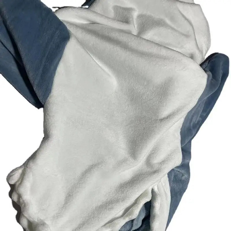 A white towel or piece of fabric is spread out over blue fabric on a flat surface, with soft folds and wrinkles—resembling the comfort of cozy pajamas.