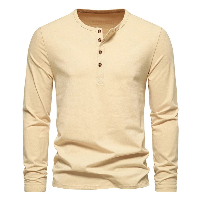 A beige long-sleeve Henley shirt with a classic design features four brown buttons on the front placket. Crafted from breathable cotton, its shown on a plain white background.