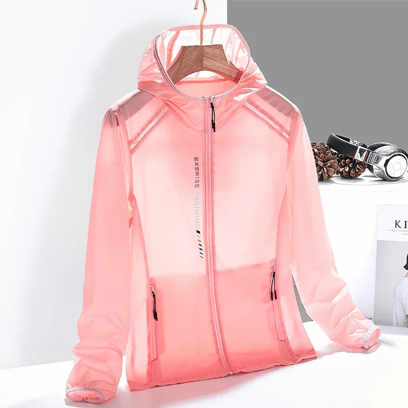 A light pink, semi-transparent hooded jacket made from quick-dry material is displayed on a hanger. The jacket has a front zipper, two zippered pockets, and is set against a minimal background with headphones and pine cones nearby.