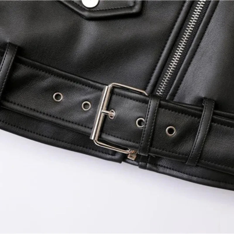 Close-up of a black leather jacket, featuring zipper pockets, a metal snap button pocket, and an adjustable waist belt with a silver buckle and metal eyelets.